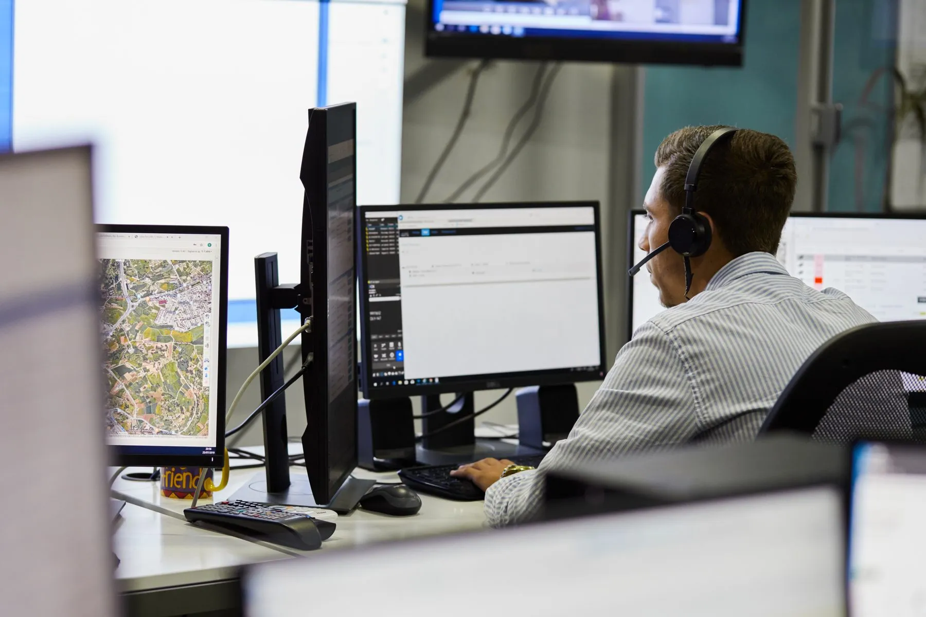 A dispatcher on the night shift with maps and bookings on several screens