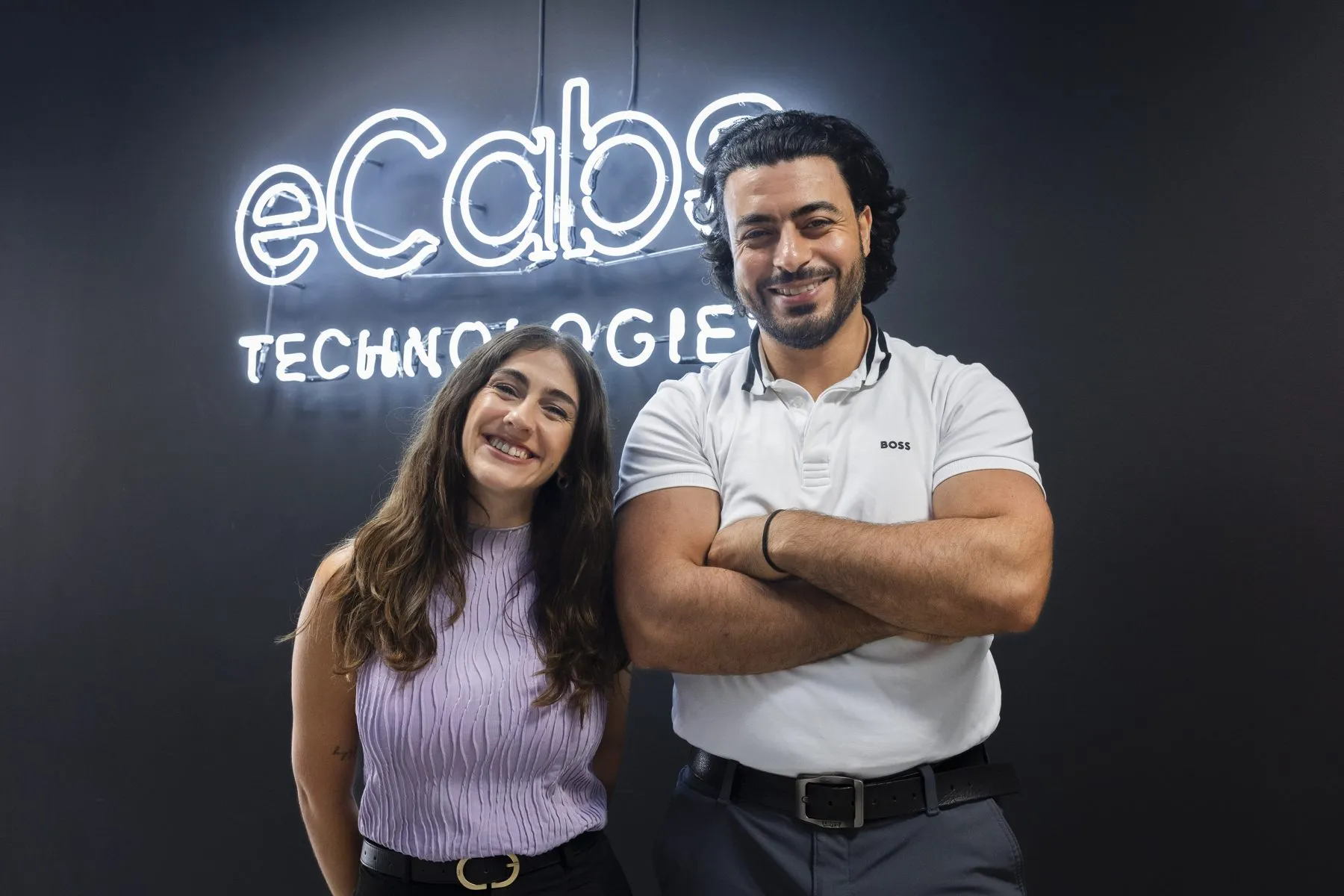 Two members of the team in front of the eCabs Technologies sign